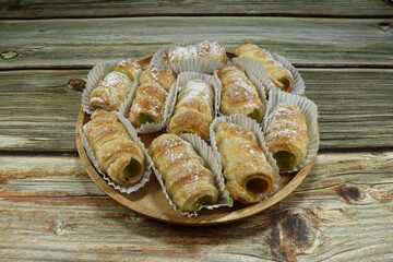 Scone of green Pandan custard cream topping with icing on the wooden plate. Famous sweet dessert or supper serving with tea. Traditional baked bread snack in party. 
