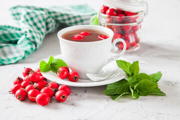 tea with a hawthorn and mint in a cup on a table, selective focus - obrazy, fototapety, plakaty