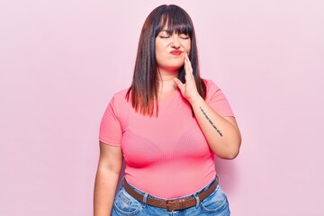 Young plus size woman wearing casual clothes touching mouth with hand with painful expression because of toothache or dental illness on teeth. dentist