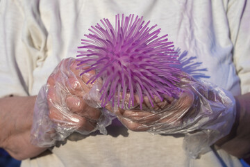 Protected by gloves, hands hold a ball looks like coronavirus close up.