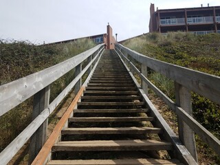 wooden stairs going up hill with railing and sand