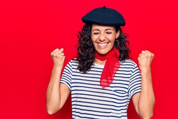 Middle age beautiful woman wearing french beret celebrating surprised and amazed for success with arms raised and eyes closed