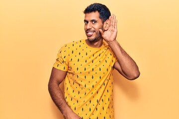 Young latin man wearing casual clothes smiling with hand over ear listening and hearing to rumor or gossip. deafness concept.