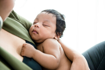 Black african newborn baby boy sleeping peacefully on mother arm with happy at home in the bed room. Beautiful African baby boy resting on his mom.Happy black family with newborn.