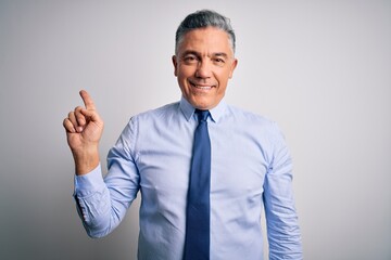 Middle age handsome grey-haired business man wearing elegant shirt and tie with a big smile on face, pointing with hand finger to the side looking at the camera.