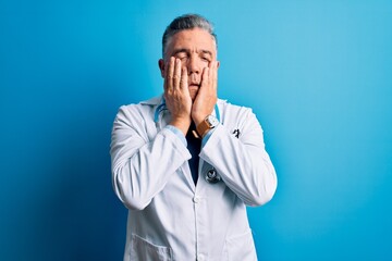 Middle age handsome grey-haired doctor man wearing coat and blue stethoscope Tired hands covering face, depression and sadness, upset and irritated for problem
