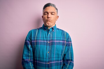 Middle age handsome grey-haired man wearing casual shirt over isolated pink background making fish face with lips, crazy and comical gesture. Funny expression.
