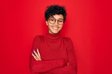 Fototapeta na wymiar Young beautiful african american afro woman wearing turtleneck sweater and glasses happy face smiling with crossed arms looking at the camera. Positive person.