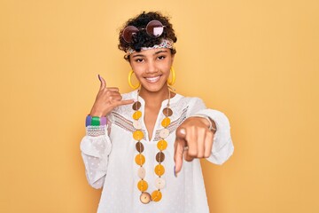 Young beautiful african american afro hippie woman wearing sunglasses and accessories smiling doing...