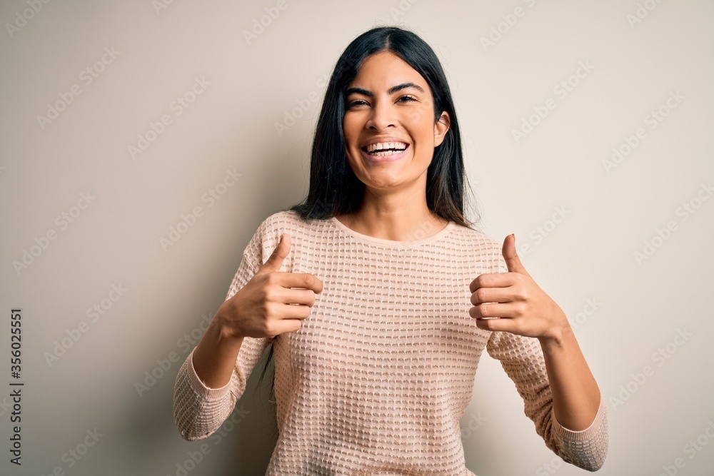 Wall mural young beautiful hispanic woman wearing elegant pink sweater over isolated background success sign do