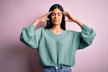 Young beautiful hispanic fashion woman wearing green sweater over pink background suffering from headache desperate and stressed because pain and migraine. Hands on head.