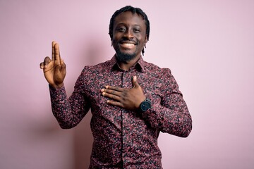 Young handsome african american man wearing casual shirt standing over pink background smiling...
