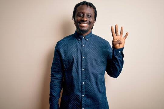 Young handsome african american man wearing casual shirt standing over white background showing and pointing up with fingers number four while smiling confident and happy.