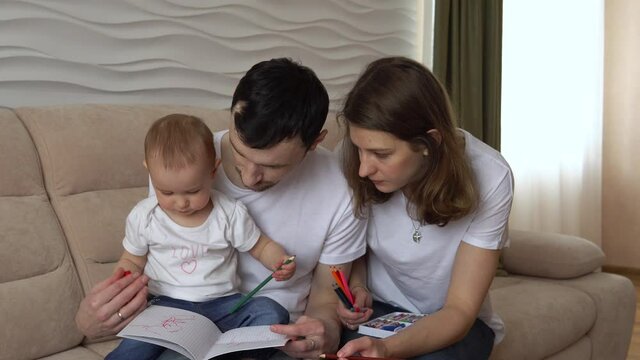 cute girl learns to draw with pencils with her parents.