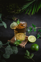 Cold black tea with fresh lime on dark background