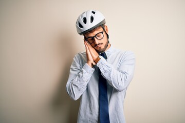 Young businessman wearing glasses and bike helmet standing over isolated white bakground sleeping tired dreaming and posing with hands together while smiling with closed eyes.