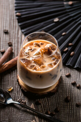 Ice coffee with cream poured over and coffee beans on a old rustic wooden table
