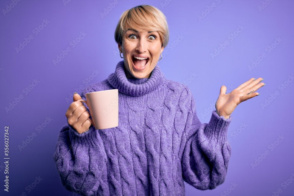 Sticker young blonde woman with short hair wearing winter sweater drinking a cup of hot coffee very happy an