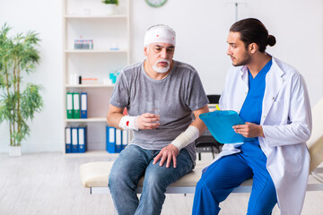 Young male doctor and old patient in first aid concept