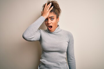 Beautiful african american girl wearing turtleneck sweater standing over white background surprised...