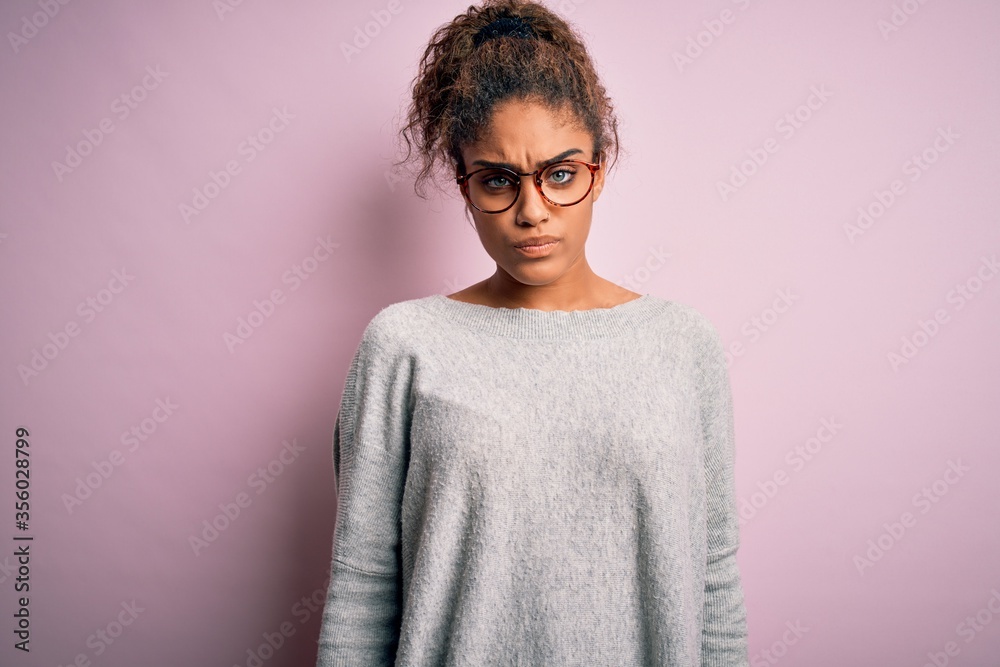 Sticker Young beautiful african american girl wearing sweater and glasses over pink background skeptic and nervous, frowning upset because of problem. Negative person.