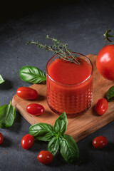 Glass of tomato juice with vegetables on wooden background
