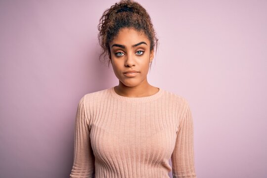 Young beautiful african american girl wearing casual sweater standing over pink background looking sleepy and tired, exhausted for fatigue and hangover, lazy eyes in the morning.