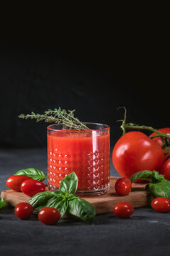 Glass of tomato juice with vegetables on wooden background