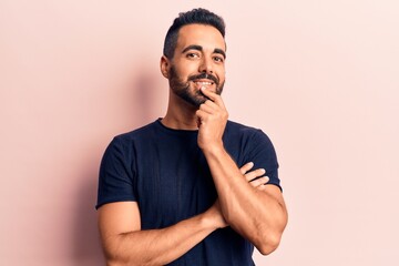 Young hispanic man wearing casual clothes smiling looking confident at the camera with crossed arms and hand on chin. thinking positive.