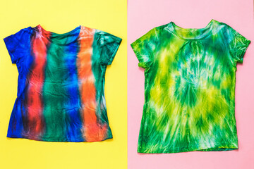 Two bright tie dye t-shirts on a two-tone background. Flat lay.