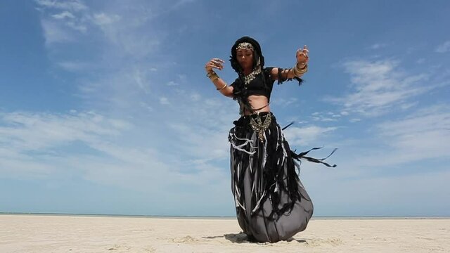 Beautiful young stylish tribal dancer. Woman in oriental costume dancing outdoors