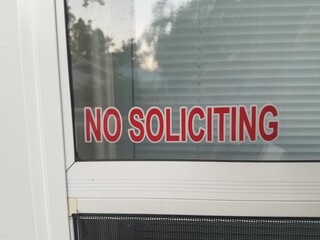 red no soliciting sign on white door