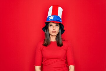 Young beautiful brunette woman wearing united states hat celebrating independence day depressed and worry for distress, crying angry and afraid. Sad expression.