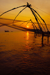 Fototapeta na wymiar silhouette of fisherman fishing with large net during sunset in cochin - india 