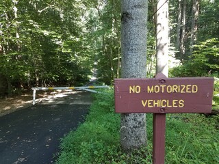 no motorized vehicles sign and asphalt trail and forest