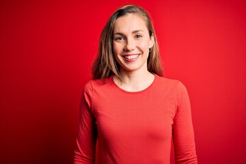Obraz premium Young beautiful blonde woman wearing casual t-shirt standing over isolated red background with a happy and cool smile on face. Lucky person.