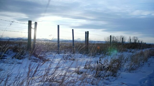 Cold winter sunset seen through fence on Alberta, Canada grasslands