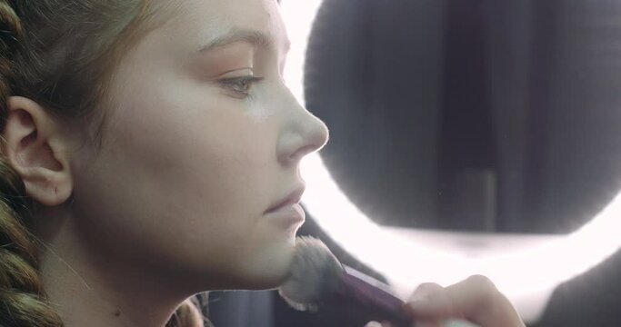 Portrait of a pretty girl, makeup artist applies makeup for a young model, studio shooting, beauty salon, 4k ProRes.