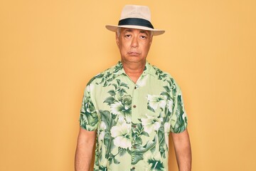 Middle age senior grey-haired man wearing summer hat and floral shirt on beach vacation depressed and worry for distress, crying angry and afraid. Sad expression.