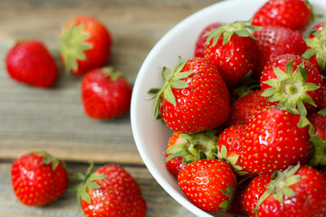 Fresh strawberries in a  bowl on wooden background.