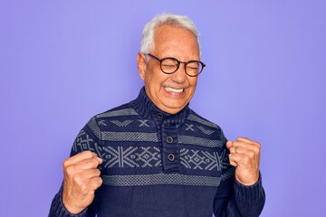 Middle age senior grey-haired man wearing glasses and winter sweater over purple background excited for success with arms raised and eyes closed celebrating victory smiling. Winner concept.