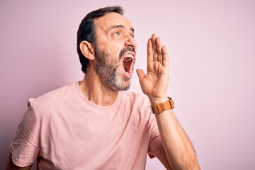 Middle age hoary man wearing casual t-shirt standing over isolated pink background shouting and...