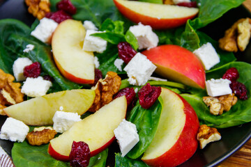 Autumn spinach salad with apple, feta cheese, walnut and dried cranberry. Healthy vegetarian food