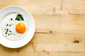 Fried eggs on plate - light wooden dinner table from above copy space