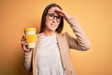 Young beautiful businesswoman drinking cup of takeaway coffee over yellow background stressed with hand on head, shocked with shame and surprise face, angry and frustrated. Fear and upset for mistake.