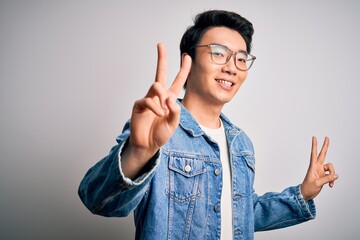Young handsome chinese man wearing denim jacket and glasses over white background smiling looking...
