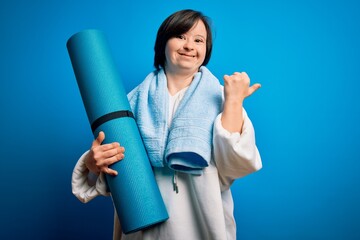 Young down syndrome fitness woman training yoga and pilates holding workout mat very happy pointing...