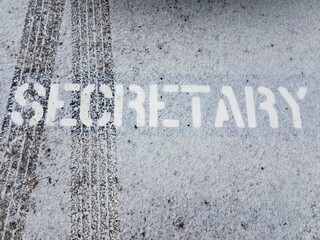 secretary sign on black asphalt with tire tracks and white snow