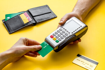Payment by credit card. Hand hold card near terminal on yellow table