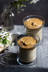 Dalgona Coffee in transparent glasses and a book on a sunlit table.